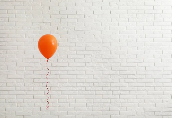 Palloncino luminoso vicino al muro di mattoni, spazio per il testo. Tempo di celebrazione — Foto Stock