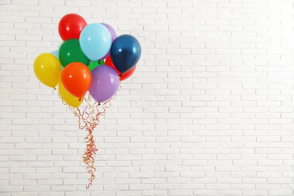 Bando de balões brilhantes perto da parede de tijolos, espaço para texto. Tempo de celebração — Fotografia de Stock