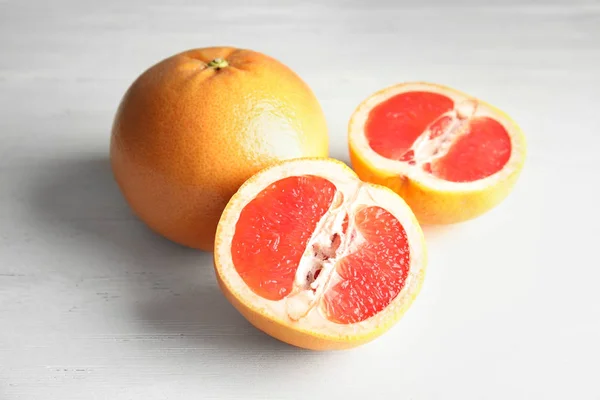 Whole and sliced tasty grapefruits on wooden table — Stock Photo, Image