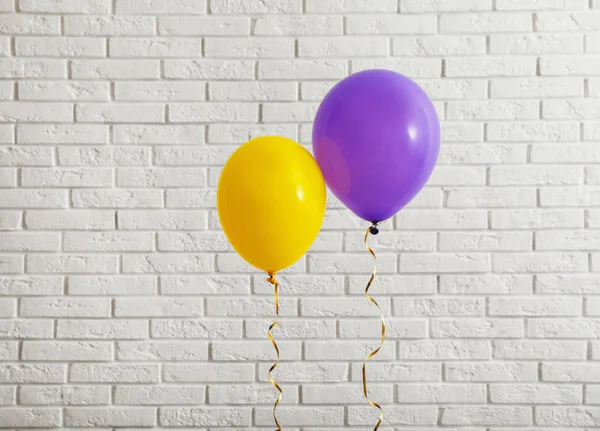 Balões brilhantes perto da parede de tijolos, espaço para texto. Tempo de celebração — Fotografia de Stock