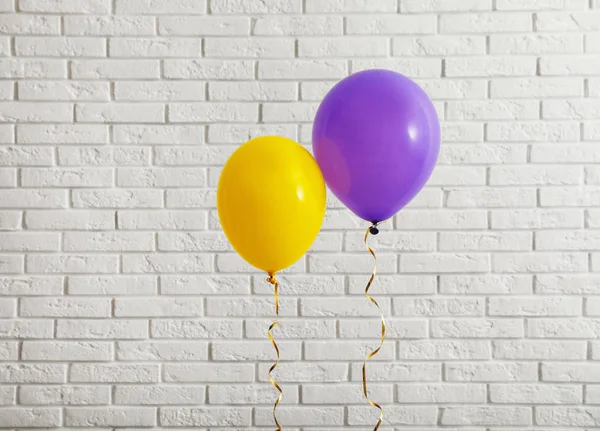 Globos brillantes cerca de la pared de ladrillo, espacio para el texto. Tiempo de celebración — Foto de Stock