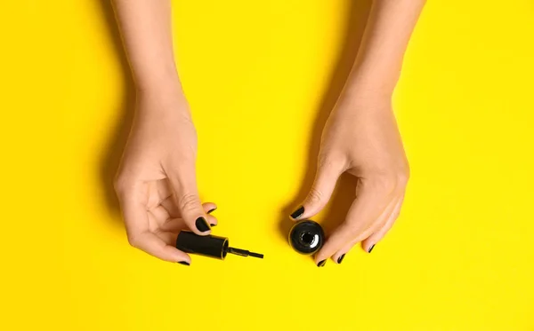 Mujer aplicando esmalte de uñas sobre fondo de color, vista superior — Foto de Stock