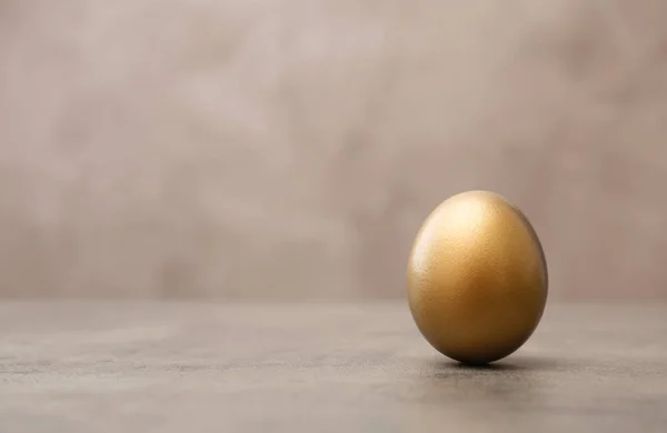 Jeden błyszczące złote jajko na stole, miejsca na tekst — Zdjęcie stockowe