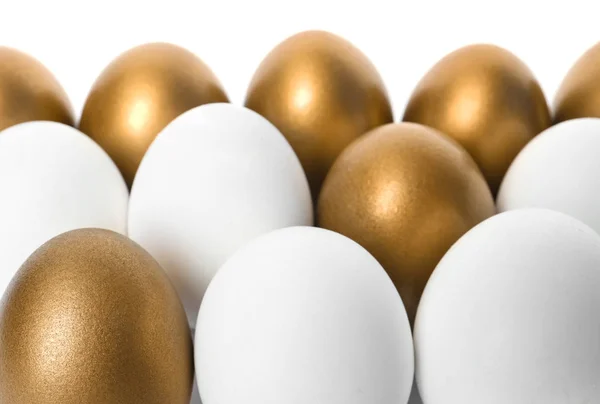 Huevos dorados entre otros sobre fondo blanco — Foto de Stock