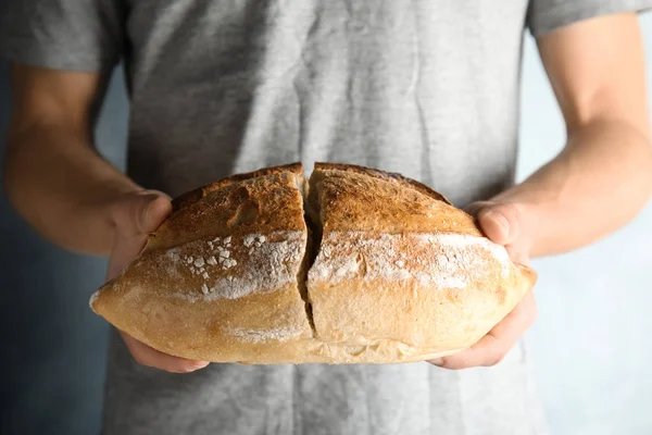 Hombre sosteniendo pan integral sobre fondo gris, primer plano — Foto de Stock
