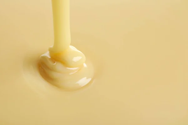 Smaczne nalewanie skondensowanego mleka jako tła, miejsca na tekst. Produkt mleczarski — Zdjęcie stockowe