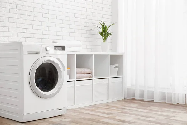Сучасна пральна машина біля цегляної стіни в інтер'єрі пральної кімнати, простір для тексту — стокове фото