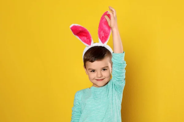 Porträt eines kleinen Jungen in Osterhasenohren Stirnband auf farbigem Hintergrund — Stockfoto