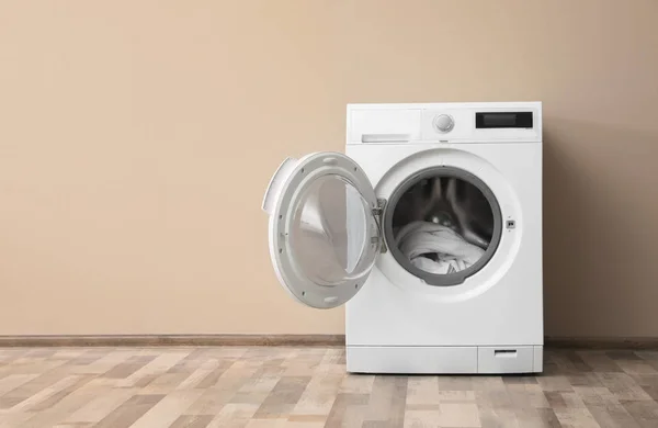 Machine à laver moderne avec buanderie près du mur de couleur, espace pour le texte — Photo