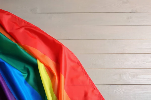 Bandera gay arco iris brillante sobre fondo de madera, vista superior con espacio para el texto. Comunidad LGBT —  Fotos de Stock