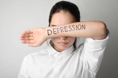 Hafif arka planda yazılı kelime depresyon ile el arkasında yüz gizleme genç kadın