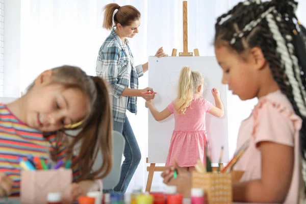 Professeur femelle avec enfant près du chevalet à la leçon de peinture à l'intérieur — Photo