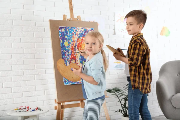 Cute little children painting on easel at home — Stock Photo, Image