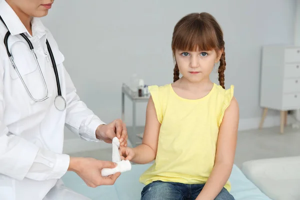 Médecin féminin appliquant un bandage sur le doigt de la petite fille à la clinique. Premiers secours — Photo