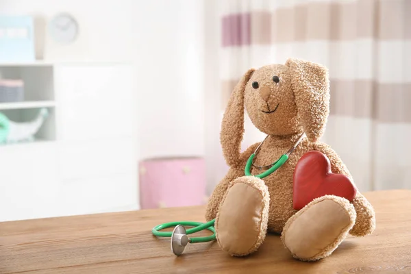 Zabawka króliczek, stetoskop i serca na stole pomieszczeniu, miejsca na tekst. Lekarz dla dzieci — Zdjęcie stockowe
