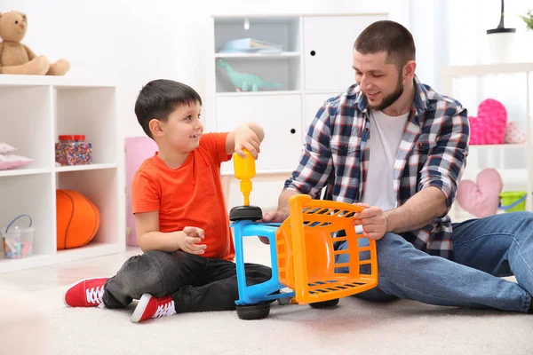 Man en zijn kind als reparateur spelen met speelgoed kar thuis — Stockfoto