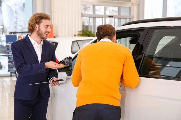 Vendedor de coches trabajando con el cliente en la concesionaria — Foto de Stock