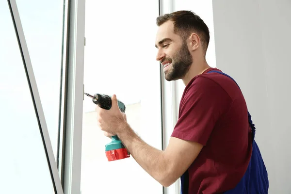 Bouwvakker met behulp van de boor tijdens het installeren van venster binnenshuis — Stockfoto