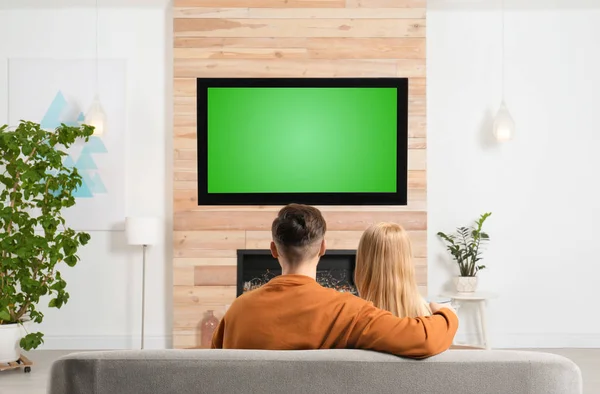 Ζευγάρι βλέποντας τηλεόραση στον καναπέ στο σαλόνι με διακοσμητικό τζάκι — Φωτογραφία Αρχείου