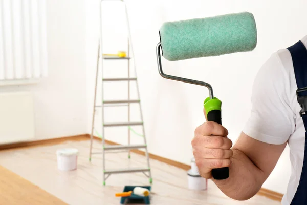 Decorador masculino com rolo de tinta na sala vazia, close up. Espaço para texto — Fotografia de Stock