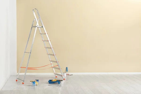 Escalera y herramientas de pintura cerca de la pared en habitación vacía —  Fotos de Stock