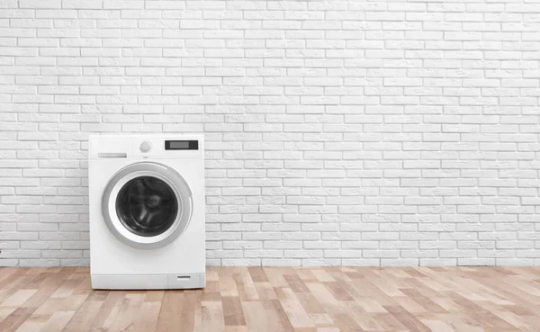 Mesin cuci modern dekat dinding bata di ruang cuci kosong, ruang teks — Stok Foto
