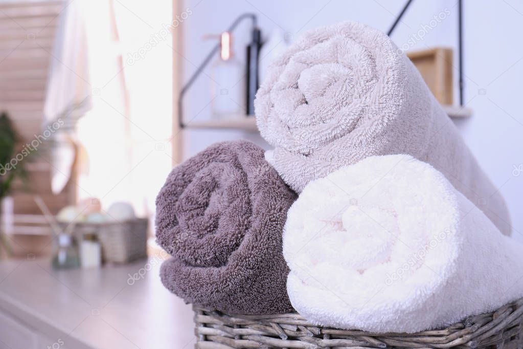 Basket with rolled fresh towels in bathroom, closeup. Space for text