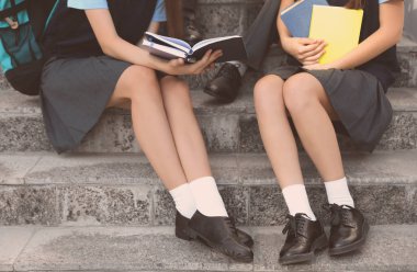Öğrenciler merdivenlerden oturan ve kitap okuma, çekim