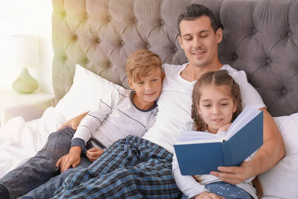 Otec četl knihu s dětmi v ložnici — Stock fotografie