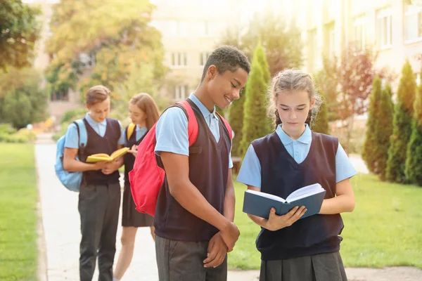 Ученики в стильной униформе читают книги на открытом воздухе — стоковое фото