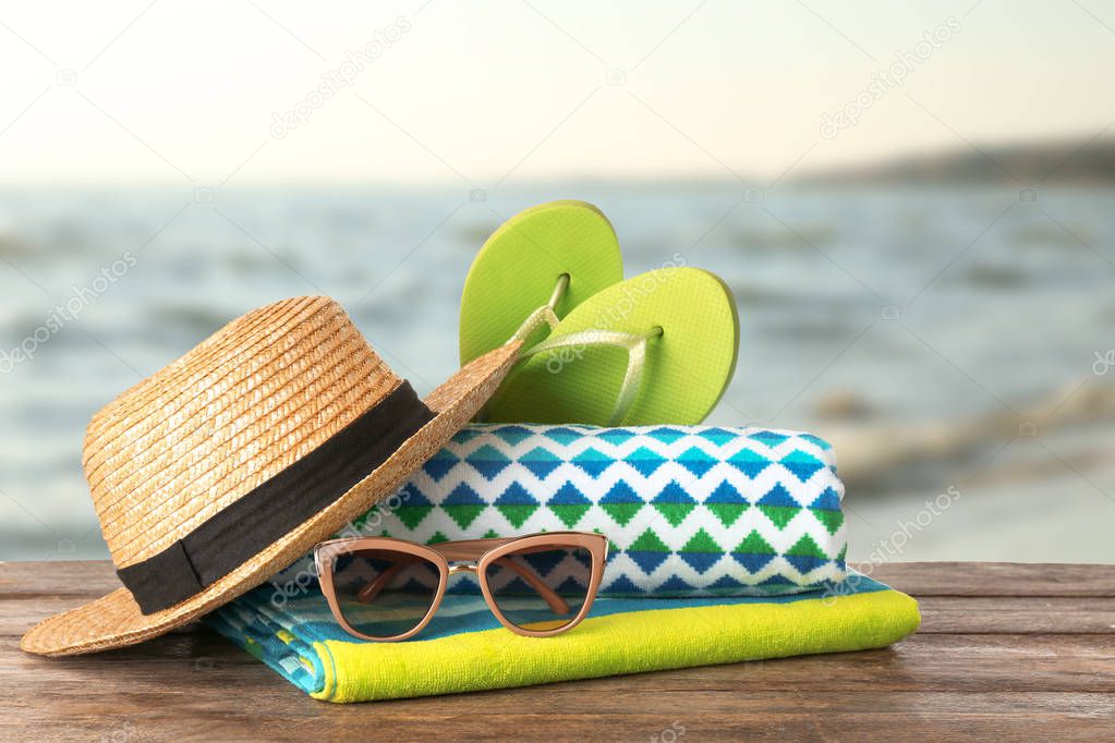 Different beach accessories on table against sea