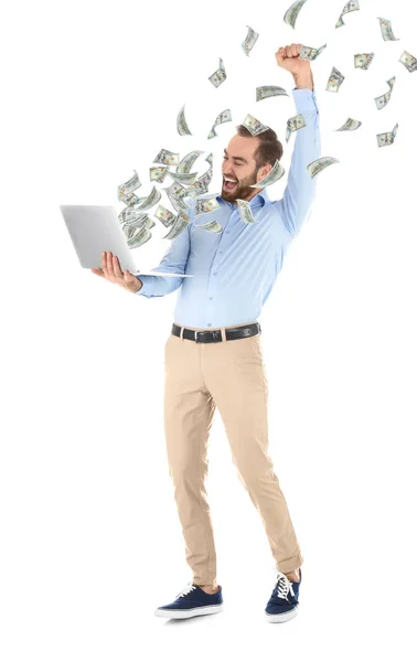 Happy man with laptop celebrating victory and flying American dollars on white background — Stock Photo, Image