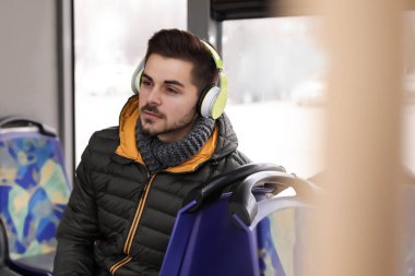 Genç adam toplu taşıma kulaklıklar ile müzik dinleme