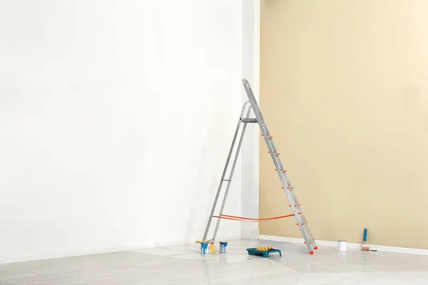 Лестница и инструменты для покраски у стены в пустой комнате — стоковое фото