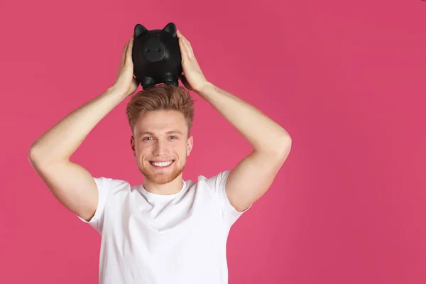 Joven con alcancía sobre fondo de color, espacio para el texto. Ahorro de dinero — Foto de Stock