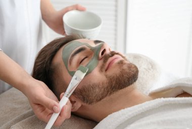 Spa salonu müşterinin yüzüne maske uygulayarak güzellik uzmanı
