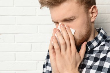 Yakışıklı genç adam tuğla duvara yakın burun üfleme. Metin alanı