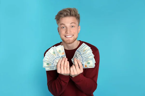 Joven hombre con dinero en el fondo de color — Foto de Stock