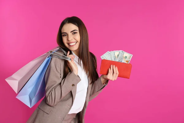 Молодая женщина с деньгами и сумки для покупок на цветном фоне. Пространство для текста — стоковое фото