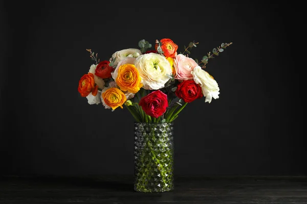 Vaas met mooie lente Ranunculus bloemen op tafel tegen donkere achtergrond — Stockfoto