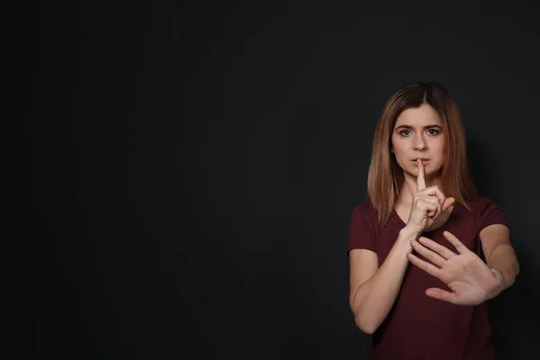 Vrouw toont Hush gebaar in gebarentaal op zwarte achtergrond, ruimte voor tekst — Stockfoto