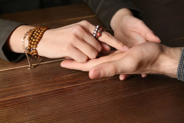 Chiromancer reading lines on man's palm at table, closeup — ストック写真