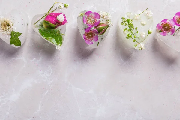 Cubos de hielo florales en forma de corazón sobre fondo de color, vista superior. Espacio para texto — Foto de Stock