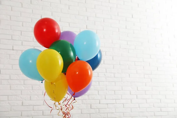 Gäng ljusa ballonger nära tegel vägg, utrymme för text. Firande tid — Stockfoto