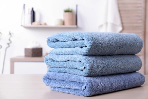 Stack of fresh towels on table in bathroom. Space for text — Stock Photo, Image