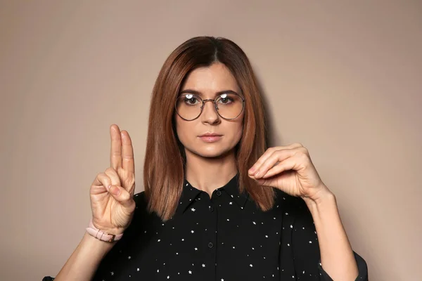 Vrouw met behulp van gebarentaal op kleur achtergrond — Stockfoto