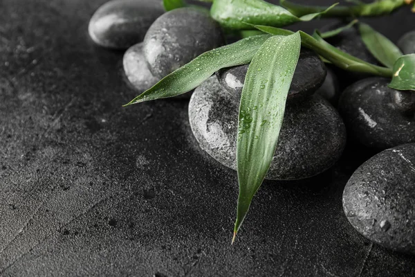 Zen pedras e folhas de bambu no fundo preto, close-up. Espaço para texto — Fotografia de Stock