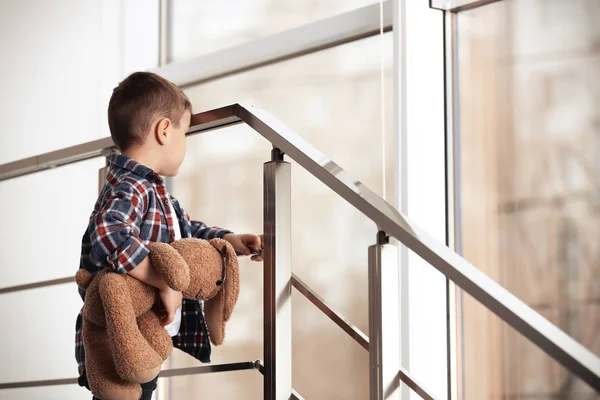 Menino triste com brinquedo nas escadas dentro de casa — Fotografia de Stock