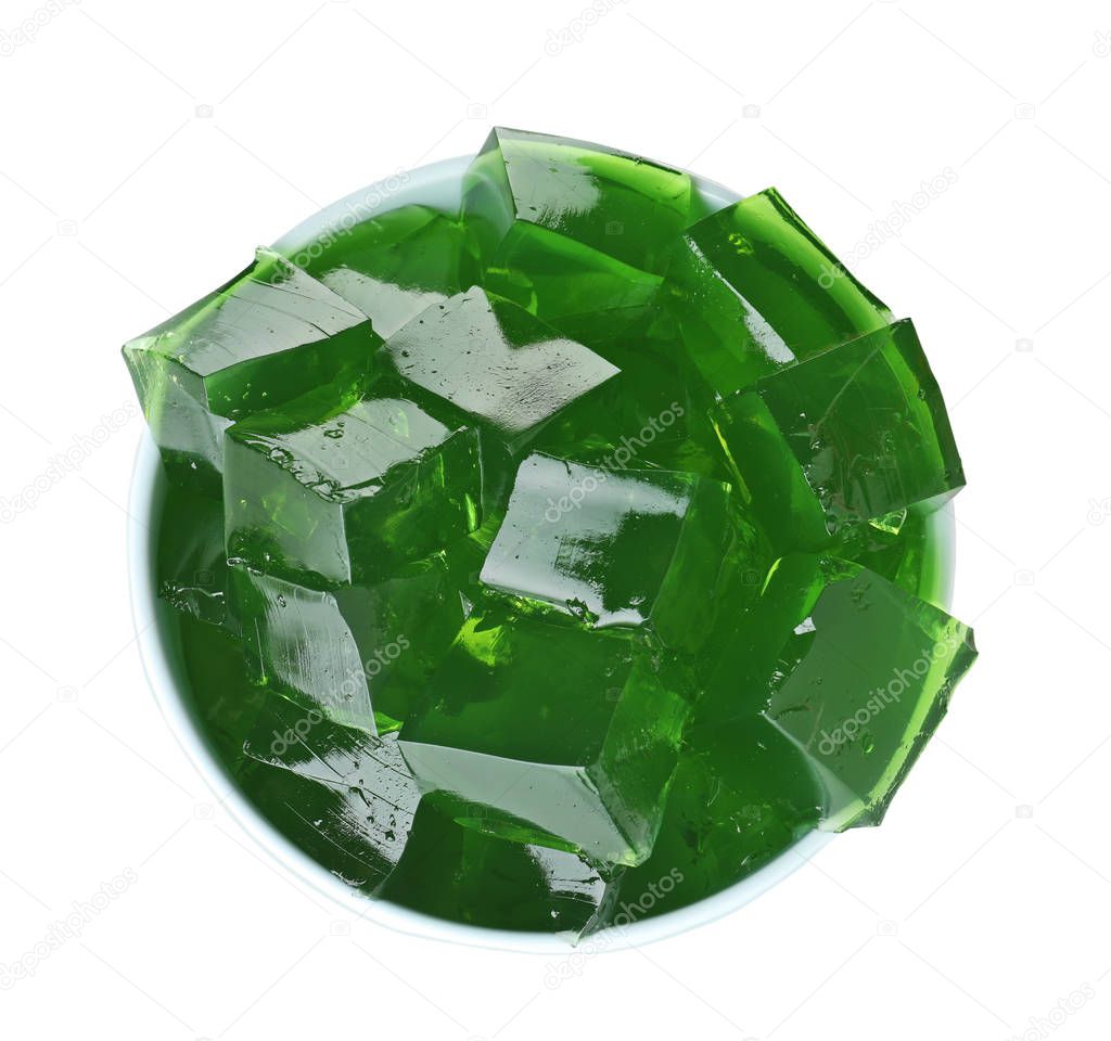 Bowl with green jelly cubes on white background, top view