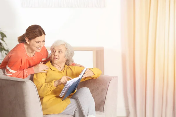 Madre anciana y su hija leyendo libro en la sala de estar, espacio para el texto —  Fotos de Stock